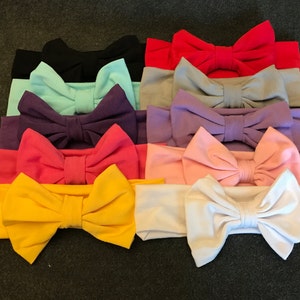 Peut inclure: Un ensemble de 12 bandeaux avec de grands nœuds en tissu de différentes couleurs, notamment jaune, rose, blanc, violet, bleu et rouge. Les bandeaux sont faits d'un matériau doux et extensible.