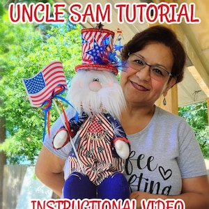Könnte beinhalten: Eine Frau hält eine Plüschpuppe des Onkel Sam, die ein rot-weiß-blaues Outfit mit einem sternenübersäten Hut trägt. Die Puppe hält eine kleine amerikanische Flagge. Die Frau trägt ein graues T-Shirt mit dem Text "Free Knitting" darauf. Das Bild ist mit "Uncle Sam Tutorial Instructional Video" betitelt.