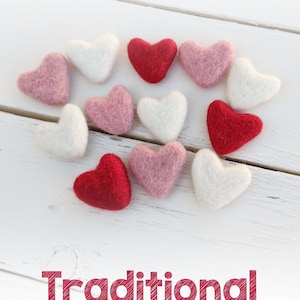 May include: A collection of felt hearts in red, dusty pink, and ivory arranged in a heart shape on a white wooden surface. The text "Traditional" is written below the hearts, with the colors listed below the text.