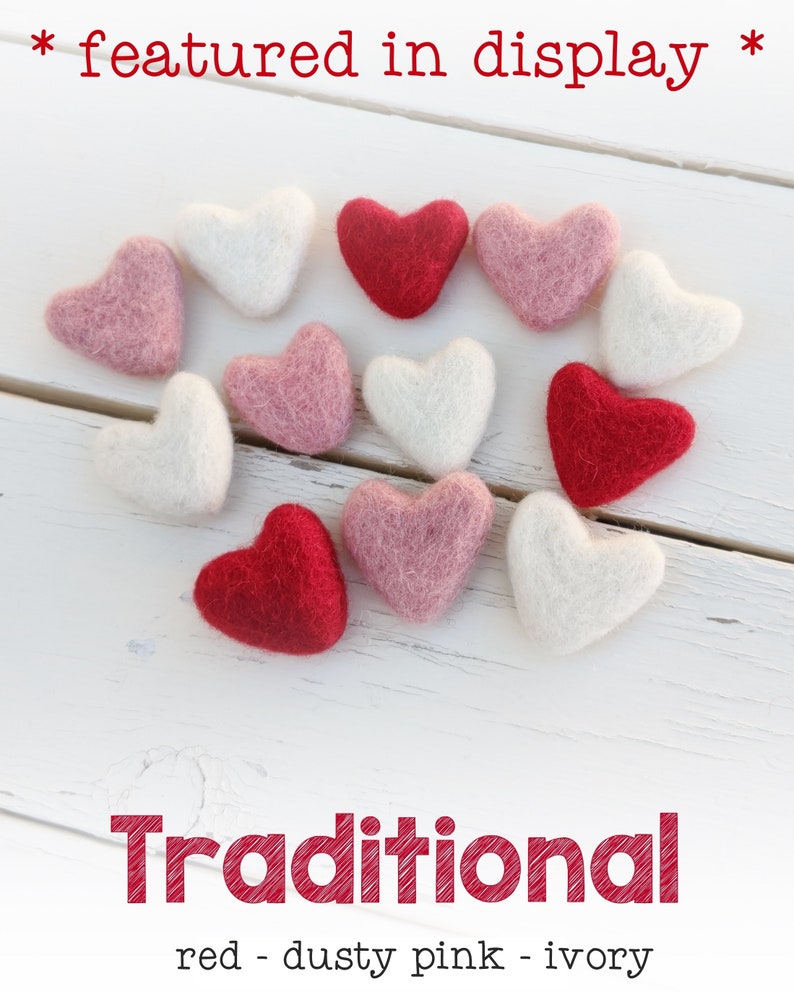 May include: A collection of felt hearts in red, dusty pink, and ivory arranged in a heart shape on a white wooden surface. The text "Traditional" is written below the hearts, with the colors listed below the text.