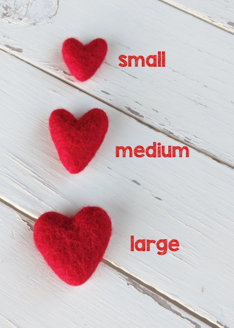 May include: Three red felt hearts of different sizes on a white wooden background. The hearts are labeled "small", "medium", and "large".