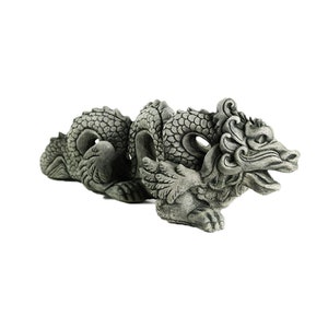 May include: A gray stone dragon statue with intricate details and a curled tail. The dragon has wings and a fierce expression.
