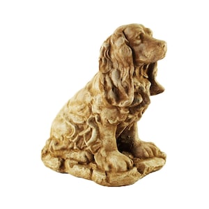 May include: A beige ceramic statue of a sitting dog with floppy ears. The dog is sculpted in a realistic style and has a detailed face.