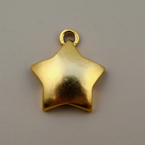 May include: A gold-colored star-shaped charm with a smooth, matte finish. The charm features a small, circular loop at the top center, designed for attachment to jewelry or other accessories. The star has five points and a solid, uniform appearance.