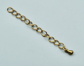 May include: A gold-toned metal jewelry extender chain featuring a series of interconnected oval links. The chain terminates with a small, smooth, teardrop-shaped charm at one end, providing an adjustable length component for necklaces or bracelets.