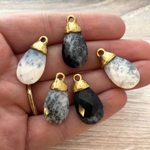 May include: Five teardrop-shaped pendants featuring faceted surfaces with a mix of white, grey, and black mottled patterns. Each pendant is topped with a textured, metallic gold-toned cap that includes a small circular loop for attachment.
