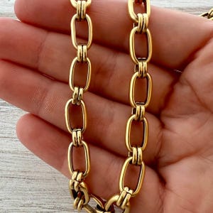 Puede incluir: Collar de cadena dorado con eslabones ovalados alargados. Los eslabones están conectados por barras decorativas más pequeñas, creando un diseño audaz y elegante. El collar tiene un acabado pulido, que refleja la luz y añade un toque de lujo.