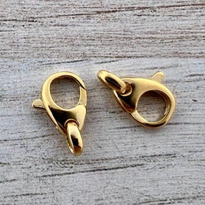 Puede incluir: Dos cierres de langosta dorados. Los cierres son de metal brillante y tienen una forma redondeada con una palanca con resorte para un cierre seguro. Están diseñados para la fabricación de joyas o manualidades.