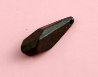 Könnte beinhalten: Ein dunkler, metallischer, länglicher Anhänger mit facettierter, geometrischer Form. Das Objekt hat eine glatte, reflektierende Oberfläche mit einem anthrazitfarbenen Finish und ein kleines, rundes Loch am schmalen Ende zur Befestigung.