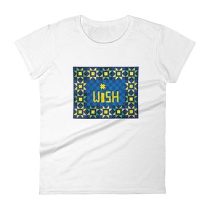 Puede incluir: Camiseta blanca para mujer con un patrón geométrico azul y amarillo y la palabra "WISH" en letras amarillas.