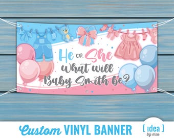 May include: A custom vinyl banner with a blue and pink theme for a baby shower. The banner features the text "He or She, What will Baby Smith be?" with illustrations of baby clothes, balloons, and teddy bears. The banner is designed by mia.
