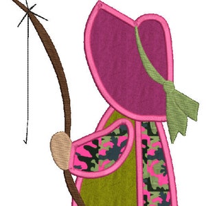 May include: A pink and green camouflage applique of a girl wearing a pink hat and holding a brown stick.