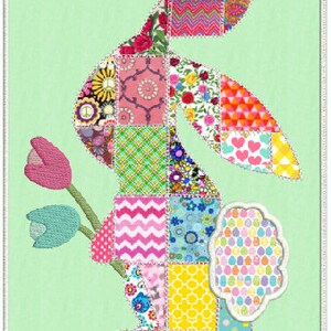 May include: A patchwork bunny rabbit with a pink, green, blue, and yellow color scheme. The bunny is holding a flower with a green stem and pink petals. The bunny is on a light green background.