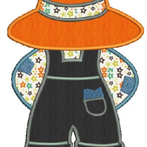 May include: An embroidered design of a figure wearing an orange sun hat with a star-patterned band. The figure is dressed in black dungarees with a blue pocket and patches, and brown shoes. The wings are decorated with a star pattern.