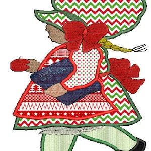 May include: A red and green Christmas-themed girl doll with a red bow, holding an apple and a book. The doll is wearing a red and green dress with a white and red pattern, a green hat with a red and green chevron pattern, and green shoes.