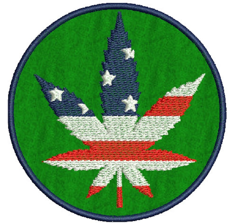 May include: A green circle with a dark blue outline features a white, red, and blue marijuana leaf design. The leaf is styled to resemble the American flag.