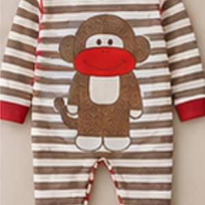 May include: A long-sleeved one-piece romper featuring a brown and white horizontal striped pattern. The garment has a red crew neckline and red sleeve cuffs. A large graphic of a brown monkey with a red face and cream-colored belly is centered.