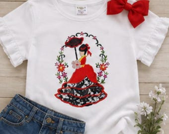 May include: A white short-sleeved t-shirt with ruffled sleeves and a red bow attached at the neckline. The center features an embroidered graphic of a figure in a red dress holding a black umbrella, surrounded by a floral frame of pink and green.