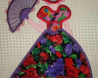 May include: Embroidered design of a woman wearing a purple and red dress with a floral pattern. She is holding a purple fan and wearing a purple hat.