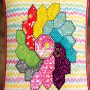 May include: A rectangular throw pillow featuring a multicolored chevron pattern background and a central floral-like applique made of various fabric hexagons in red, yellow, teal, green, pink, and purple, with a pink piped edge border.