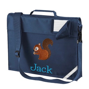 Könnte beinhalten: Eine marineblaue Schultasche mit einem Eichhörnchen-Design und dem Namen "Jack", der auf der Vorderseite gestickt ist. Die Tasche hat einen Schultergurt und einen Tragegriff.