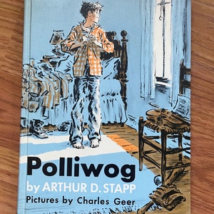 Puede incluir: Una portada de libro vintage con fondo azul y un niño con una camisa a cuadros de pie en una habitación. El título del libro es "Polliwog" de Arthur D. Stapp, con ilustraciones de Charles Geer.