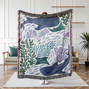 K&ouml;nnte beinhalten: Eine gewebte Tapisserie-Decke mit einer farbenfrohen Unterwasser-Szene mit einem Walhai, Rochen, Korallen, Quallen und Fischen. Die Decke hat einen wei&szlig;en Hintergrund mit blauen, gr&uuml;nen und violetten Akzenten.
