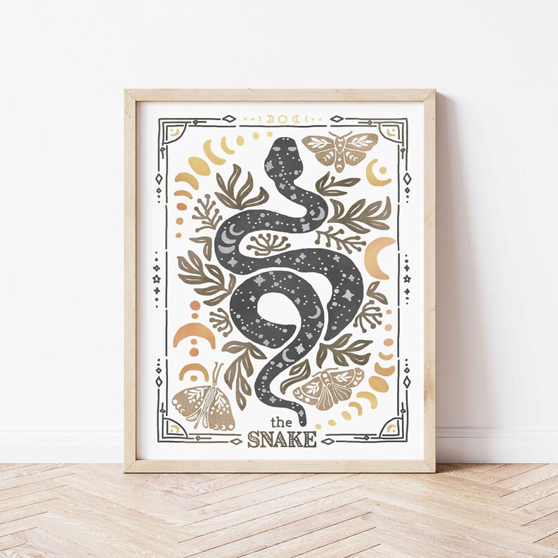 K&ouml;nnte beinhalten: Ein gerahmter Druck mit einer schwarzen Schlange mit wei&szlig;en Sternen, umgeben von goldenen und braunen floralen Designs, Monden und Schmetterlingen. Der Text "the SNAKE" befindet sich am unteren Rand des Drucks.