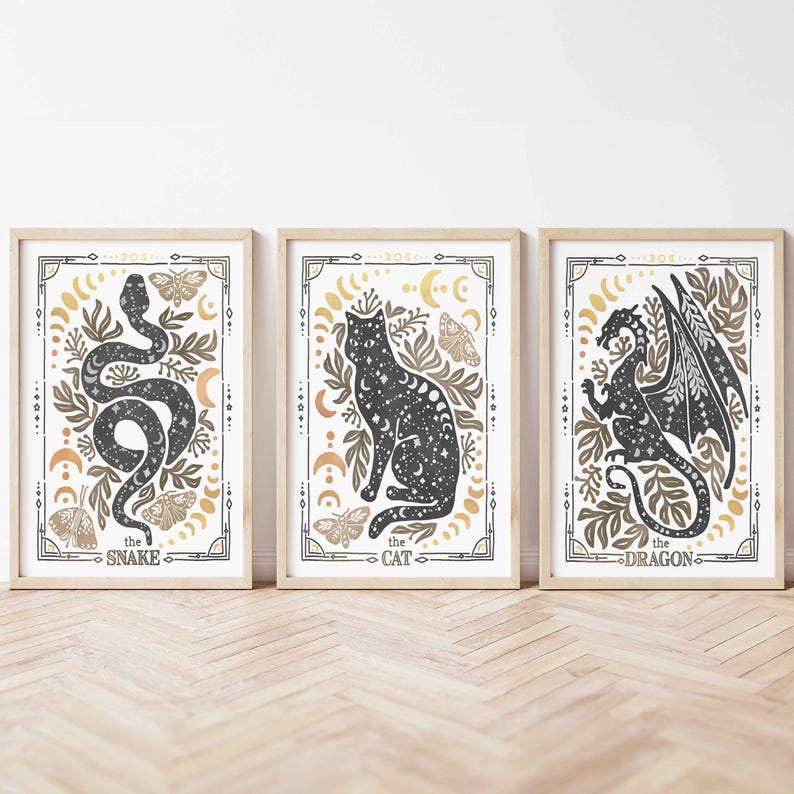 K&ouml;nnte beinhalten: Drei gerahmte Drucke mit einer schwarzen und wei&szlig;en Silhouette einer Schlange, einer Katze und eines Drachen. Jeder Druck hat einen goldenen und braunen Hintergrund mit einem floralen Design und den Text "the snake", "the cat" und "the dragon".