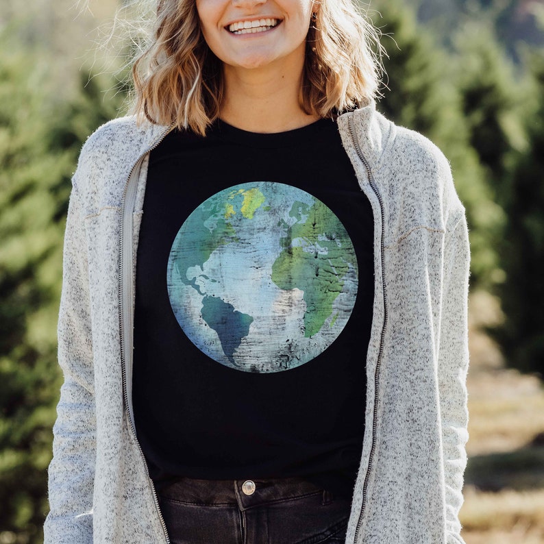 May include: A black t-shirt with a graphic of a blue and green earth on it. The earth is painted in a distressed style with a wood grain texture.