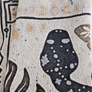 A mystical woven blanket featuring a celestial snake design filled with moons and stars, surrounded by botanical elements, crescent moons, and twinkling stars in an intricate tarot-inspired border. The rich, detailed artwork creates a witchy, astrology-inspired aesthetic, perfect for adding a magical and mystical touch to any space. Ideal as a cozy throw, bedspread, or statement wall tapestry for those who love tarot, celestial themes, and occult decor