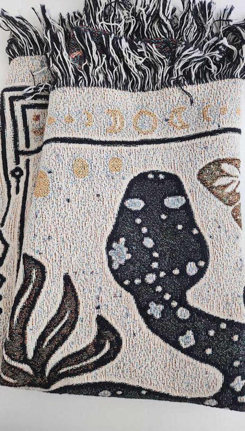 A mystical woven blanket featuring a celestial snake design filled with moons and stars, surrounded by botanical elements, crescent moons, and twinkling stars in an intricate tarot-inspired border. The rich, detailed artwork creates a witchy, astrology-inspired aesthetic, perfect for adding a magical and mystical touch to any space. Ideal as a cozy throw, bedspread, or statement wall tapestry for those who love tarot, celestial themes, and occult decor