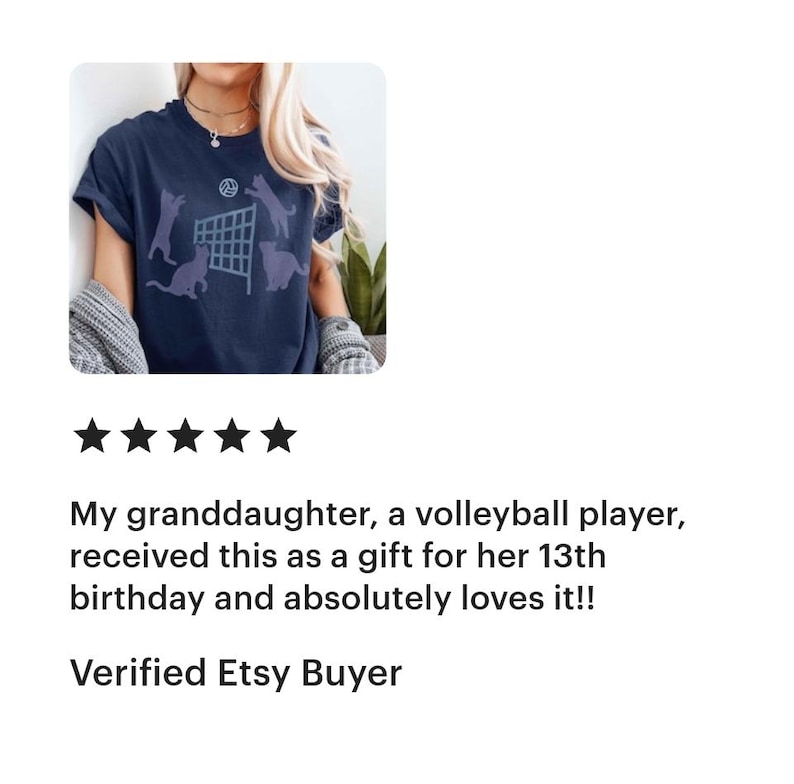 May include: A navy blue t-shirt with a volleyball net graphic and cats jumping over the net. The text "My Cats Are Better Than Yours" is printed on the shirt.
