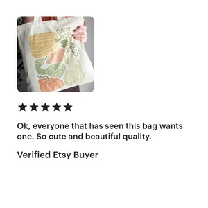 Puede incluir: Bolso tote de color crema con una colorida ilustraci&oacute;n de varias calabazas y calabacines en tonos amarillos, verdes y naranjas. El bolso tiene un dise&ntilde;o sencillo con forma rectangular y dos asas.