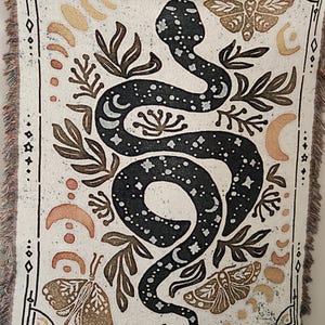A mystical woven blanket featuring a celestial snake design filled with moons and stars, surrounded by botanical elements, crescent moons, and twinkling stars in an intricate tarot-inspired border. The rich, detailed artwork creates a witchy, astrology-inspired aesthetic, perfect for adding a magical and mystical touch to any space. Ideal as a cozy throw, bedspread, or statement wall tapestry for those who love tarot, celestial themes, and occult decor