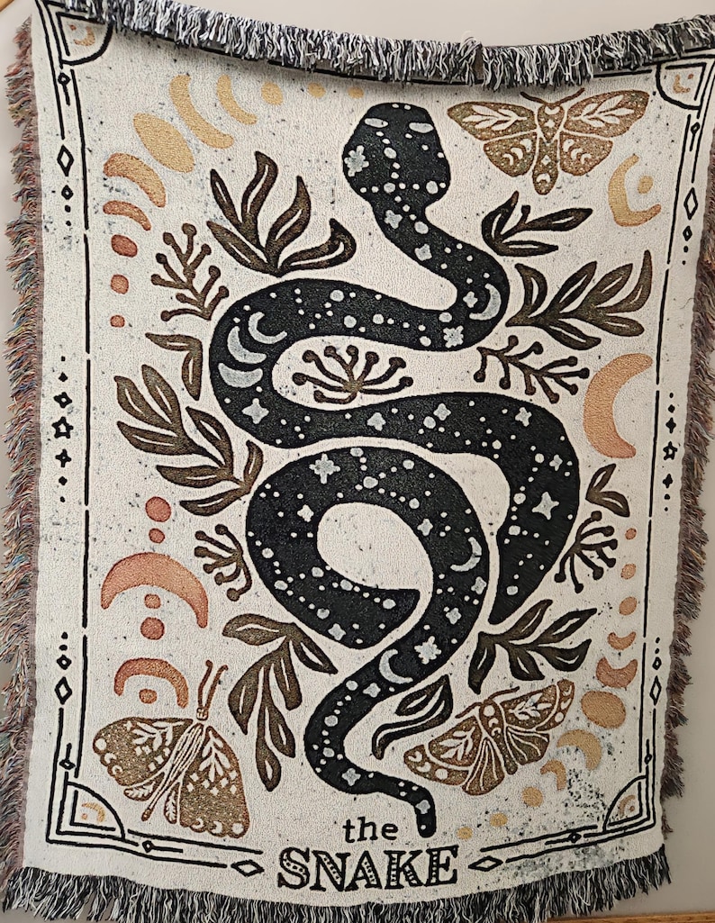 A mystical woven blanket featuring a celestial snake design filled with moons and stars, surrounded by botanical elements, crescent moons, and twinkling stars in an intricate tarot-inspired border. The rich, detailed artwork creates a witchy, astrology-inspired aesthetic, perfect for adding a magical and mystical touch to any space. Ideal as a cozy throw, bedspread, or statement wall tapestry for those who love tarot, celestial themes, and occult decor