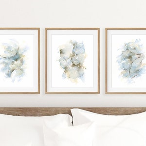Peut inclure: Ensemble de trois peintures abstraites à l'aquarelle dans des tons de bleu et de gris, encadrées dans du bois naturel.
