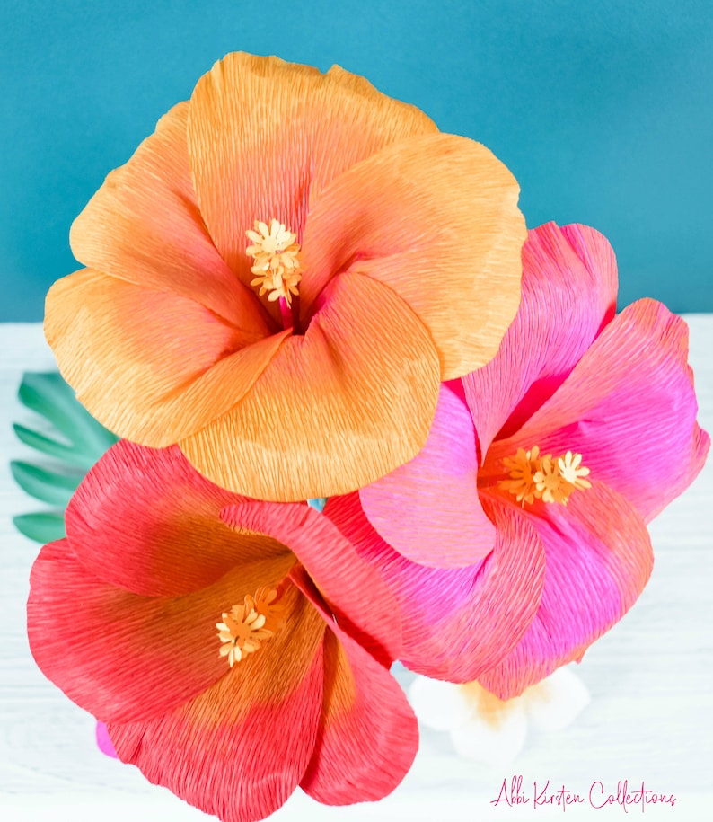 Puede incluir: Tres grandes flores de hibisco de papel en tonos naranja, rosa y rojo. Las flores est&aacute;n hechas de papel de seda arrugado y tienen un aspecto realista.