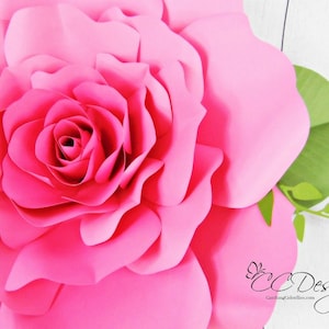 May include: A large, pink paper rose with a green stem and leaves. The rose is made of multiple layers of paper, creating a 3D effect.