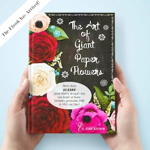 May include: The Art of Giant Paper Flowers ebook cover features a chalkboard background with white text and illustrations of paper flowers in red, white, pink, and blue. The text on the cover reads "The Art of Giant Paper Flowers" and "More than 15 EASY giant flower designs you can make at home. Includes printable PDF & SVG cut files!" with the author's name, Abbi Kirsten, at the bottom.