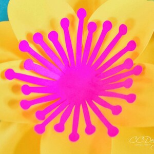 May include: A bright yellow paper flower with a pink center. The center is made of paper and has a starburst design.