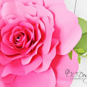 May include: A large, pink paper rose with a green stem and leaves. The rose is made of multiple layers of paper, creating a 3D effect.