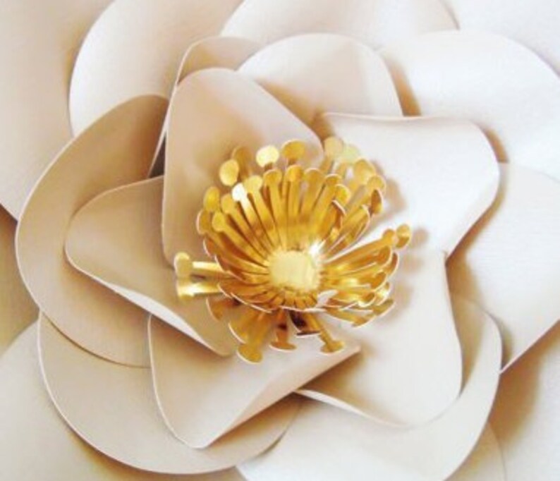 May include: A large, white paper flower with a gold center. The flower has multiple layers of petals and is a popular craft project.