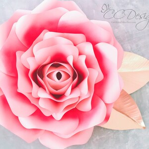 May include: A large, pink paper rose with a layered, ruffled center. The rose is accented with two gold paper leaves.