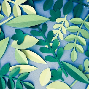 May include: A collection of green paper leaves of various shapes and sizes, arranged on a blue background. The leaves are cut out and layered to create a three-dimensional effect.