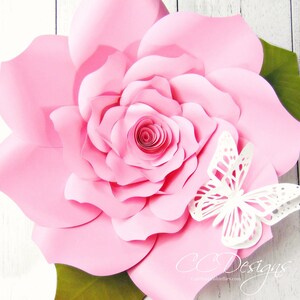 May include: A large pink paper flower with a white butterfly on the side. The flower is made of multiple layers of paper and has a spiral center. The butterfly is delicate and intricate.