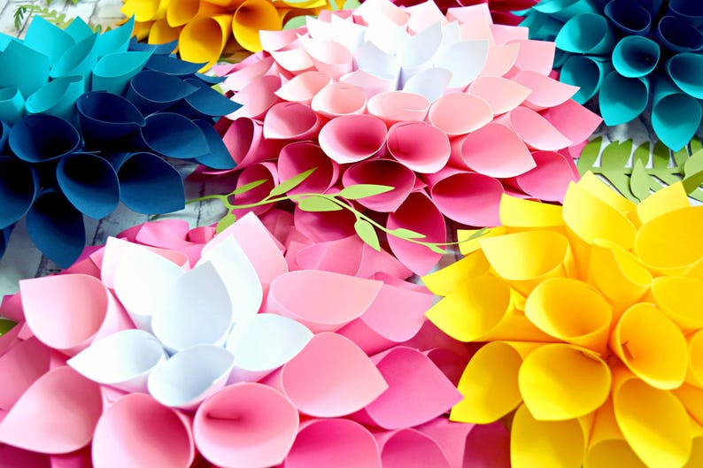 May include: A collection of paper flowers in various colors, including teal, yellow, pink, and white. The flowers are made of folded paper and have a layered, three-dimensional appearance.