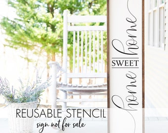 May include: A white wooden sign with the text "Sweet Home" written in black cursive script. The sign is leaning against a white rocking chair on a porch.