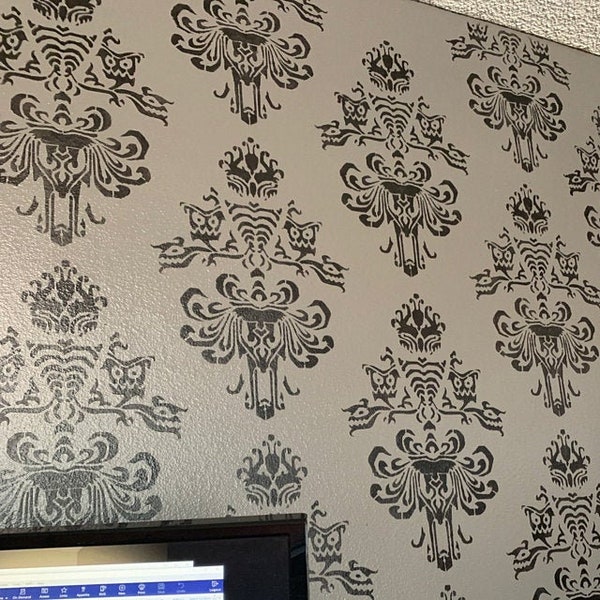 May include: A wall painted with a repeating pattern of a black and white haunted mansion design. The design features a spooky mansion with a tower and a ghost with a long, flowing sheet.