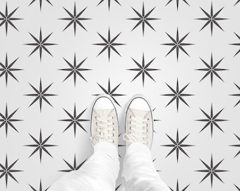 Puede incluir: Un par de zapatos de lona blancos con cordones negros se encuentran sobre un suelo blanco con un patrón repetitivo de formas de estrellas negras.